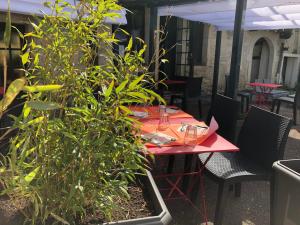 une table rouge avec des plantes sur une terrasse dans l'établissement Auberge du Renard'eau, à Bèze