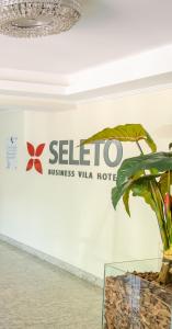 a sign for a hotel with a plant on a wall at Seleto Hotel in Volta Redonda