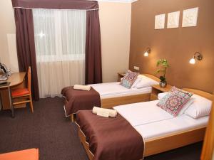 Habitación de hotel con 3 camas y mesa en ALFA Hotel & Wellness Miskolctapolca, en Miskolctapolca