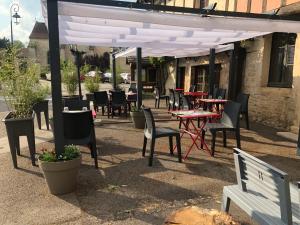 d'une terrasse avec des tables et des chaises sous un auvent blanc. dans l'établissement Auberge du Renard'eau, à Bèze