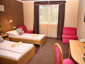 a room with two beds and a table and chairs at ALFA Hotel & Wellness Miskolctapolca in Miskolctapolca