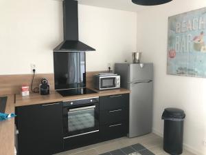 La cuisine est équipée d'un four micro-ondes et d'un réfrigérateur. dans l'établissement Maison Cosy avec terrasse à 10 minutes du centre ville, à La Rochelle