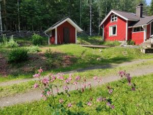 ein rotes Haus und ein Feld mit rosa Blumen in der Unterkunft Metsäpirtti in Kolinkylä