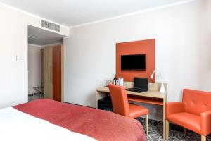a hotel room with a bed, chair, desk and television at Hotel Schild in Vienna