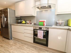 a kitchen with white cabinets and a stove top oven at Godrevy Cottage in Hayle
