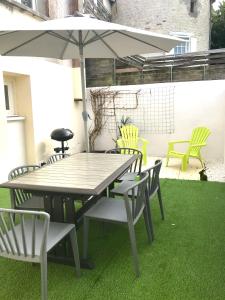 une table et des chaises avec un parasol sur une pelouse dans l'établissement Maison Cosy avec terrasse à 10 minutes du centre ville, à La Rochelle 3 autres photos