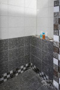 ducha con paredes de azulejos blancos y negros en Alopronoia Sea Breeze en Síkinos