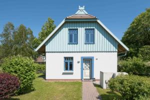 uma pequena casa branca com um telhado verde em Ferienhaussiedlung Strandperlen Weidenhof 6b (Typ IX) em Wustrow