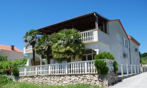 a house with a white fence and a palm tree at Villa Sabina - Apartments Kroatien in Ražanac