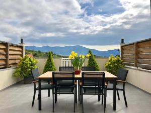 una mesa y sillas en un patio con montañas al fondo en Propriété Malva appartement agava en Alata