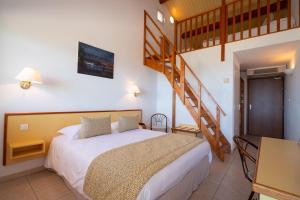 ein Schlafzimmer mit einem Bett und einer Wendeltreppe in der Unterkunft Hotel Les Galets in Saint-Florent
