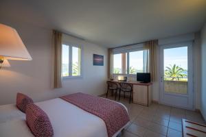 sypialnia z 2 łóżkami i biurkiem z telewizorem w obiekcie Hotel Les Galets w mieście Saint-Florent