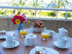 una mesa de madera con productos para el desayuno y zumo de naranja en Hotel Les Galets, en Saint-Florent