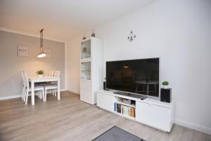 ein Wohnzimmer mit einem TV und einem Esstisch in der Unterkunft Papillon Wohnung 18-3 in Boltenhagen