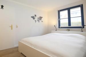 ein weißes Schlafzimmer mit einem weißen Bett und einem Fenster in der Unterkunft Papillon Wohnung 18-3 in Boltenhagen