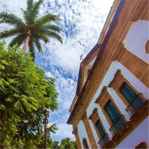ein hohes Gebäude mit einer Palme neben einem Gebäude in der Unterkunft Casa Colibri - Praias e Cachoeiras in Paraty