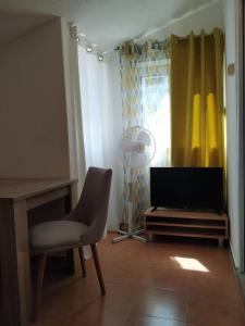 ein Wohnzimmer mit einem TV, einem Stuhl und einem Fenster in der Unterkunft Apartmani Abeona in Budva