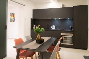uma cozinha preta com uma mesa e algumas cadeiras laranja em Mori Siciliani House em Aci Castello