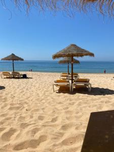 un gruppo di ombrelloni e sedie a sdraio in spiaggia di Casa Bravo a Querença