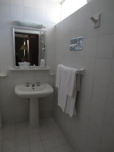 ein weißes Badezimmer mit einem Waschbecken und einem Spiegel in der Unterkunft Hotel Las Palmas Midway Inn in Matehuala