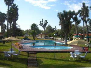 a swimming pool with tables and chairs and umbrellas at Hotel Las Palmas Midway Inn in Matehuala