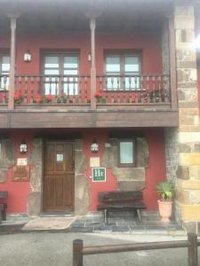 Casa roja con puerta de madera y balcón en LA CASONA DE RALES VILLAVICIOSA en Rales