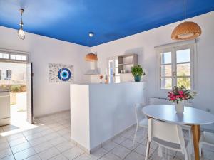 a kitchen with blue ceilings and a table and chairs at Aria Kimolos Residence in Kimolos