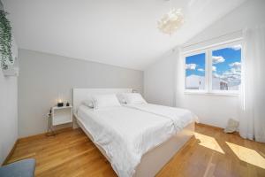 a white bedroom with a bed and a window at Family Petrov Apartments in Vodice