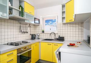 a kitchen with yellow cabinets and a sink at Family Petrov Apartments in Vodice