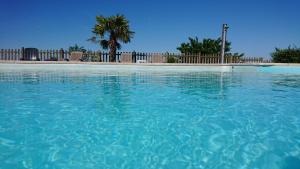 a swimming pool with blue water in front of a fence at Gîtes & Chambres d'hôtes Peyrecout in Laparrouquial
