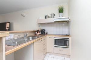 una pequeña cocina con fregadero y microondas en Inner City One Bedroom Apartment 27, en Cairns