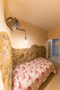 1 dormitorio con 1 cama con pared de piedra en Affittacamere Nonna Nana, en Tirli