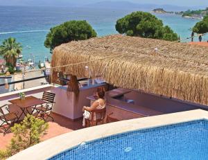 a woman sitting at a table next to a swimming pool at Rosy Suites Hotel in Kuşadası
