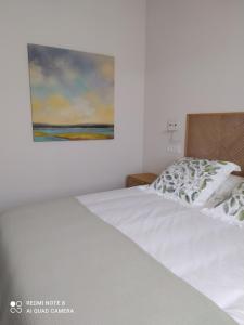 sypialnia z białym łóżkiem i obrazem na ścianie w obiekcie Apartamentos Pontedeume Riadoeume w mieście Puentedeume