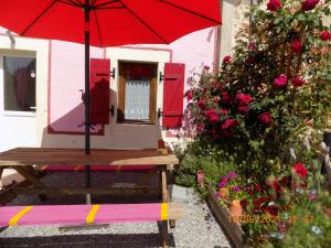 una mesa de picnic con una sombrilla roja delante de una casa en Aux Roses en Vrolle