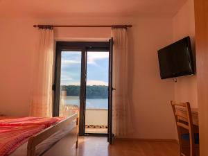 a bedroom with a bed and a television and a window at Apartments Palit Rab in Rab
