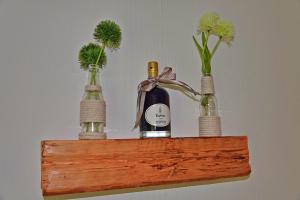 trzy butelki wina na drewnianej półce z kwiatami w obiekcie Harzapart Apartment 3 "Hirsch" w mieście Walkenried