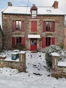 a brick house with red doors in the snow at Ar Litorienn in Paimpont