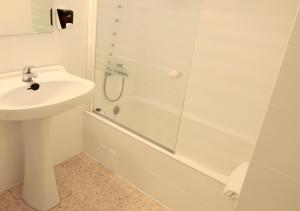 a white bathroom with a sink and a shower at Hostal Lara in Llança +6 photos