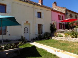 une maison avec un banc et un parasol dans la cour dans l'établissement Les Papillons, à Vrolle