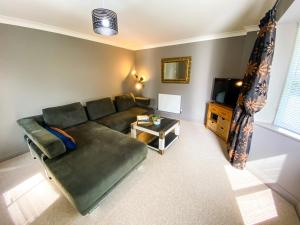 a living room with a green couch and a television at Kings Quarters Boutique Rooms in Hartford