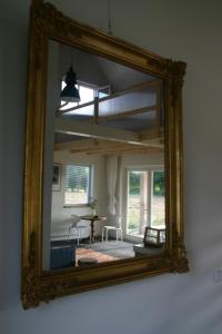a mirror reflecting a living room with a table at Huisje Wevers in Bathmen