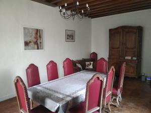 een eetkamer met een tafel en rode stoelen bij La Ferme de Spoir in Mignières