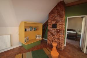 een woonkamer met een boekenplank en een bakstenen muur bij La Ferme de Spoir in Mignières