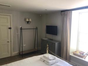 a bedroom with a bed and a tv and a window at The Farmhouse at Bodnant Welsh Food in Conwy