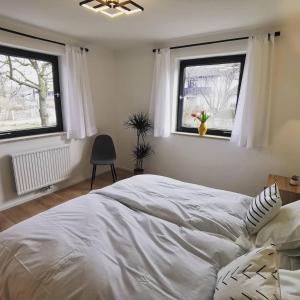 PettingにあるModerne Ferienwohnungen mit Designbadの白いベッドと2つの窓がある寝室