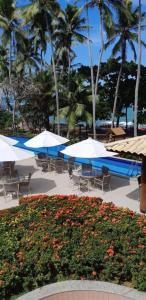 a resort with tables and umbrellas and a swimming pool at Enseada Praia do Forte in Praia do Forte