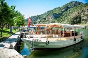 ein Boot liegt an einem Dock im Wasser in der Unterkunft Dalyan Hotel Nish Caria in Dalyan