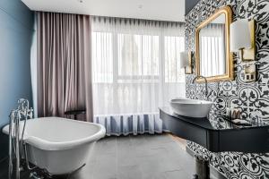 een badkamer met een bad, een wastafel en een spiegel bij St Martins Lodge in Leicester