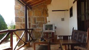 a living room with a tv and a stone wall at Finca Casa Loma Barichara in Barichara